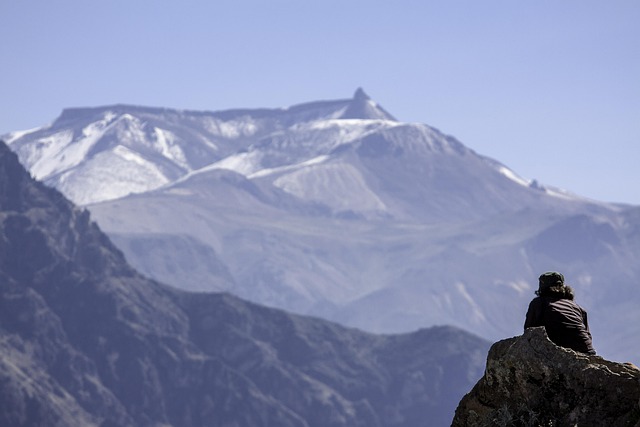 Guy sitting and enjoying the bit snowy hills and green trees at Tiffin Top, Nainital – adventure tourism spot.