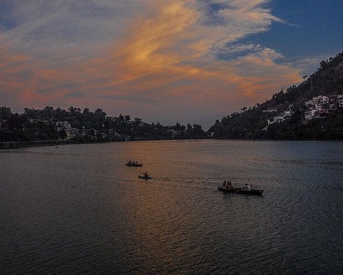alt= "Golden sunrise over Naini Lake, captured from Dorothy’s Seat in Nainital – serene Himalayan view with boathouses and misty hills."