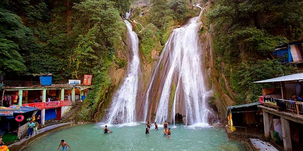 Scenic view of Kempty Falls in Mussoorie with water cascading down rocky cliffs surrounded by lush greenery