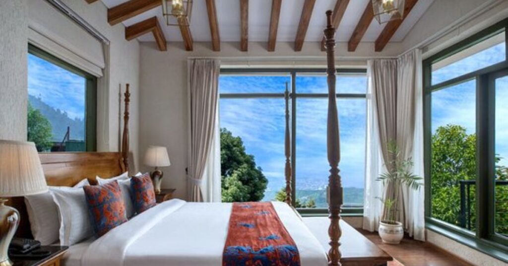 "Cozy hotel room in Mussoorie with a wooden balcony overlooking rain-drenched hills and misty valleys - perfect monsoon retreat in the mountains."