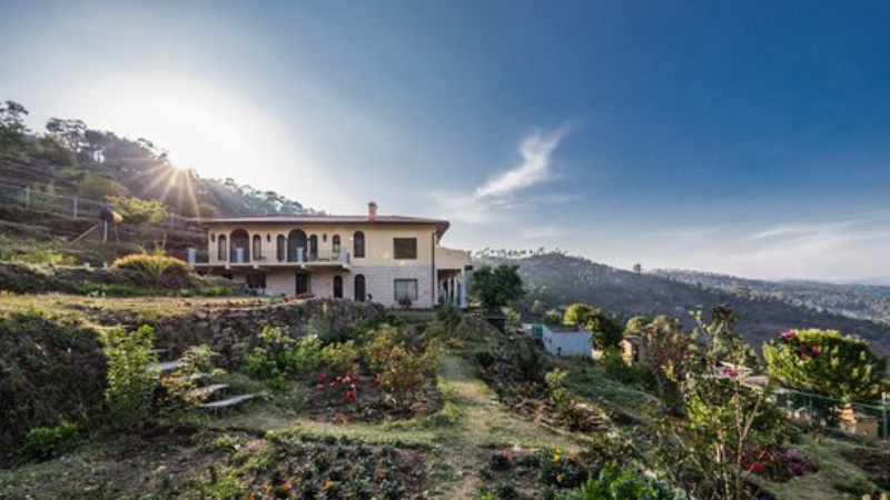 "A breathtaking sunrise view from Peora Village, with golden hues illuminating the snow-capped Himalayan peaks and rolling green valleys below."